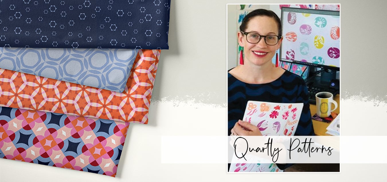 Folded fabrics in navy hexagon, blue circle, orange floral, and pink geometric prints; designer holding pattern sketches at desk with digital polka dot design on monitor, text reads Quartly Patterns