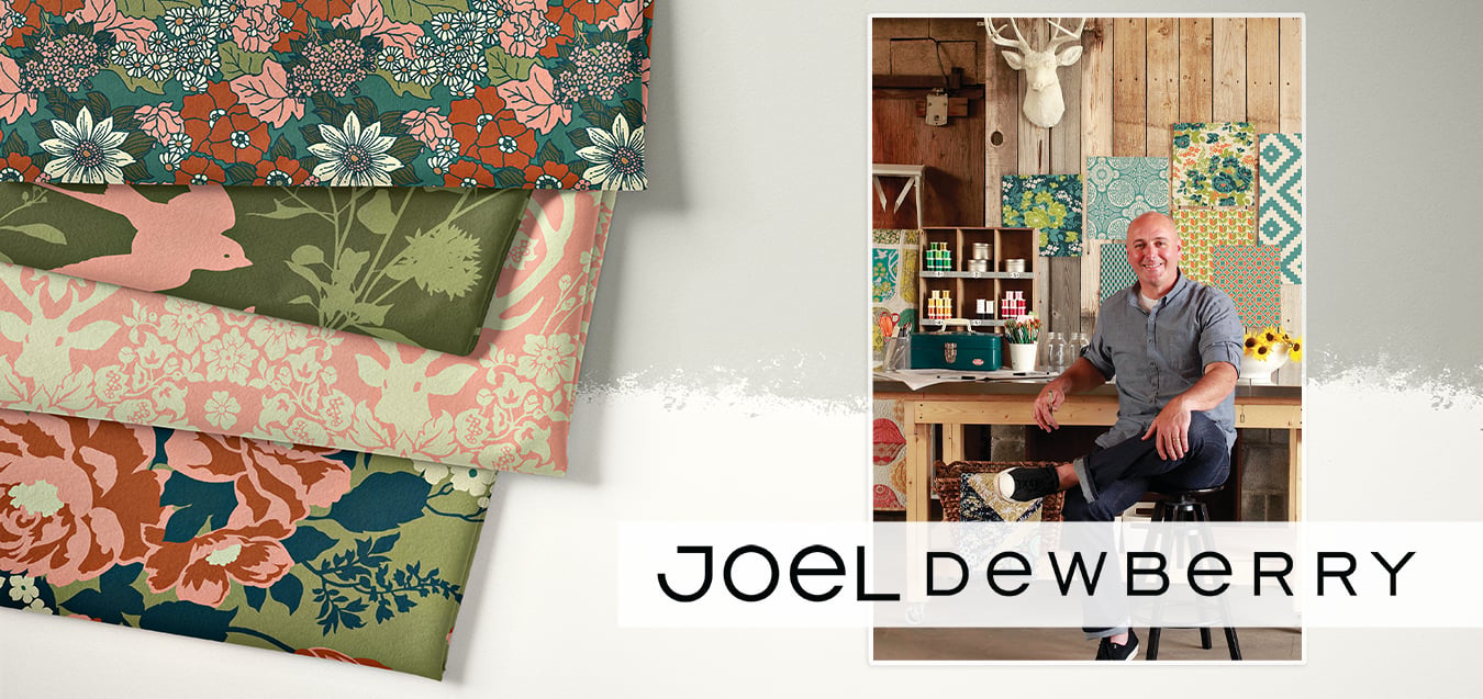 Folded floral fabrics in coral, teal, and olive prints beside a photo of designer Joel Dewberry seated in a rustic studio