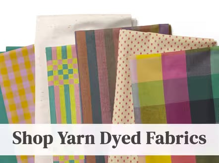 Stack of yarn dyed fabrics in plaid, stripe, and dot patterns with teal, mustard, pink, and cream tones