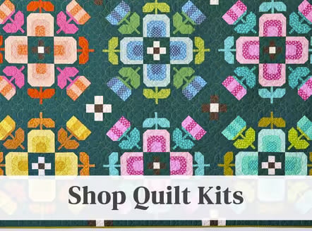 Colorful geometric floral medallion quilt in pink, blue, yellow and green on dark teal background, with 'Shop Quilt Kits' text overlay